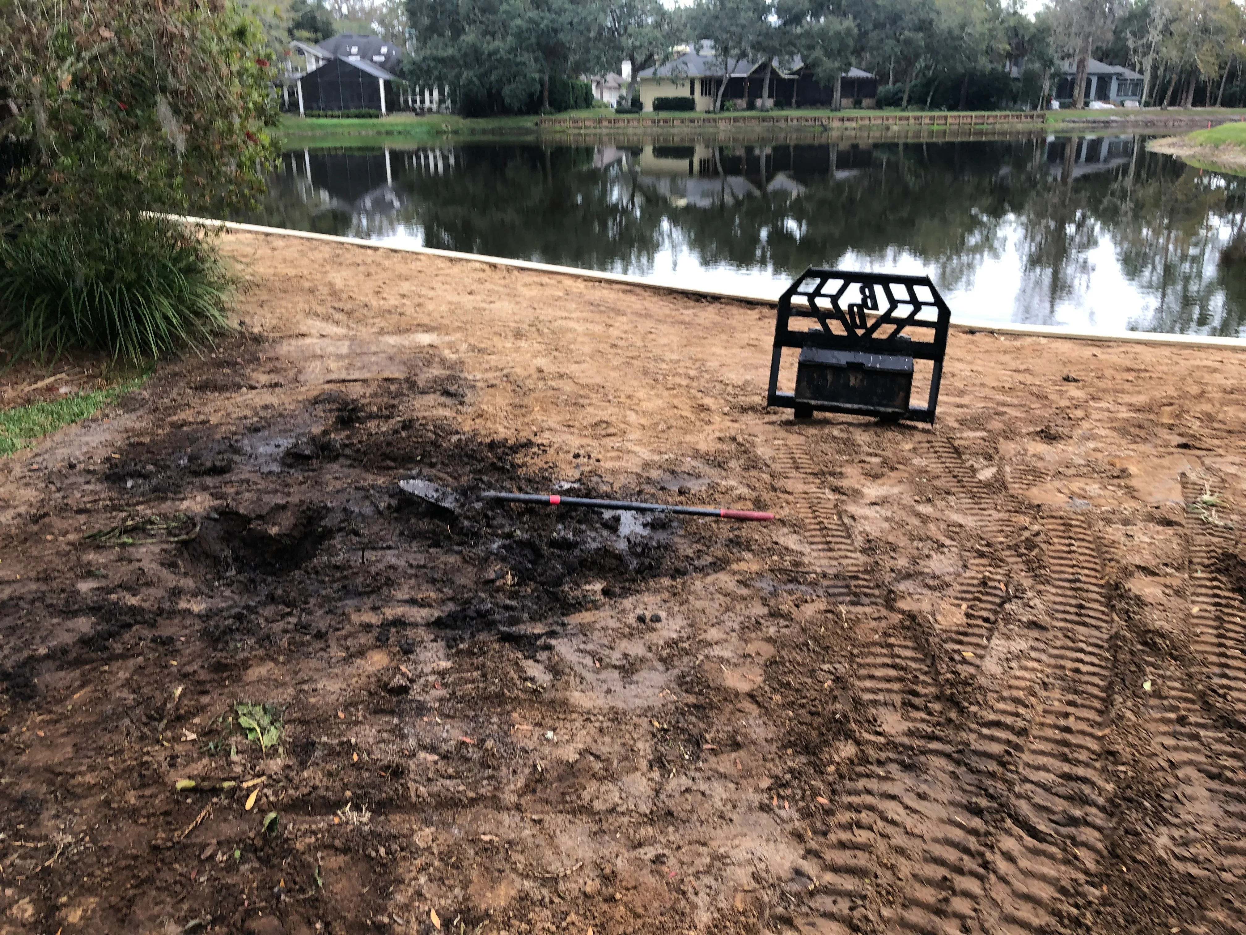 Graded soil with rake patterns and white landscape edging along waterfront property