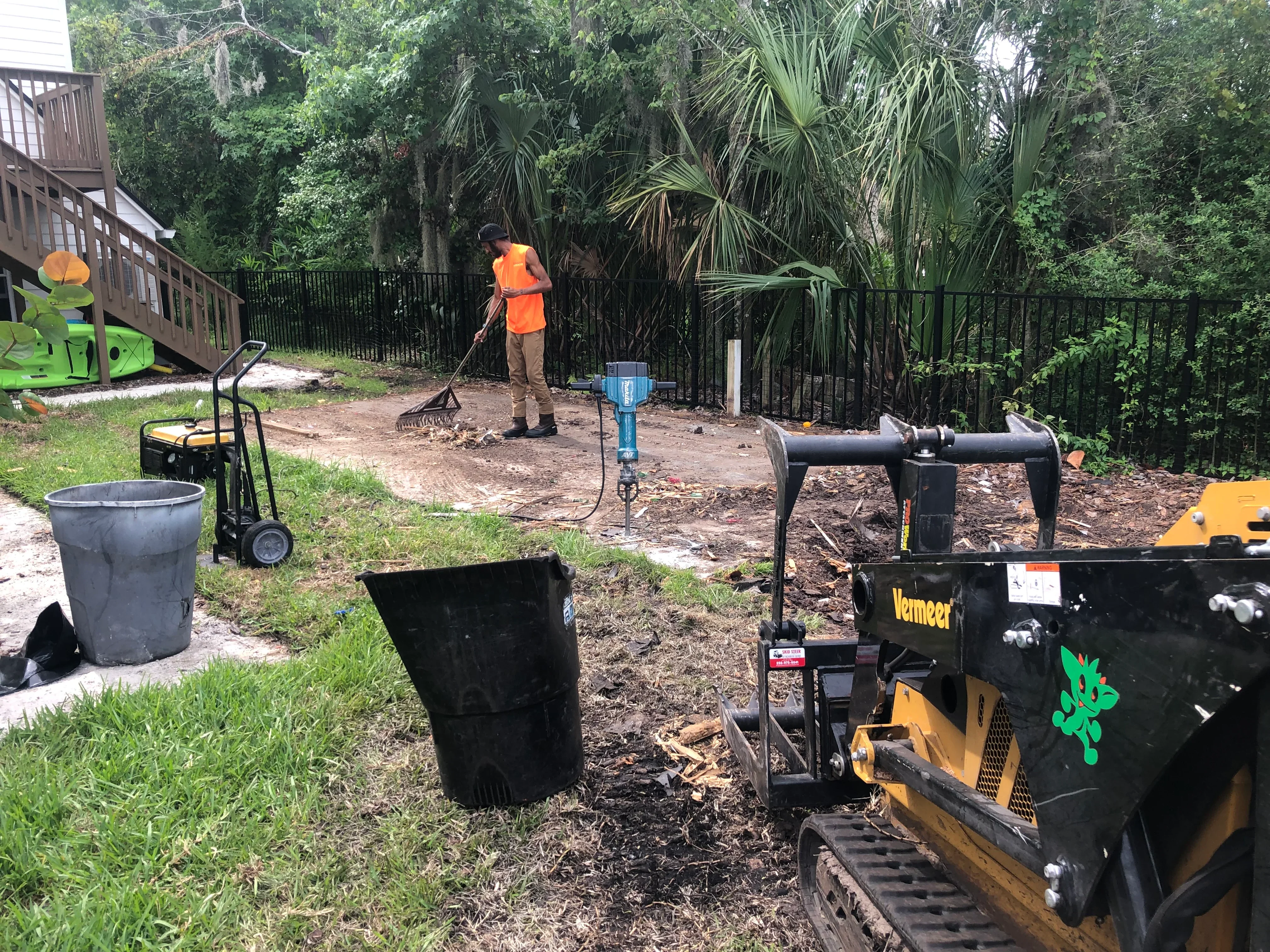 Excavation equipment and worker grading residential lot with mulch and soil preparation