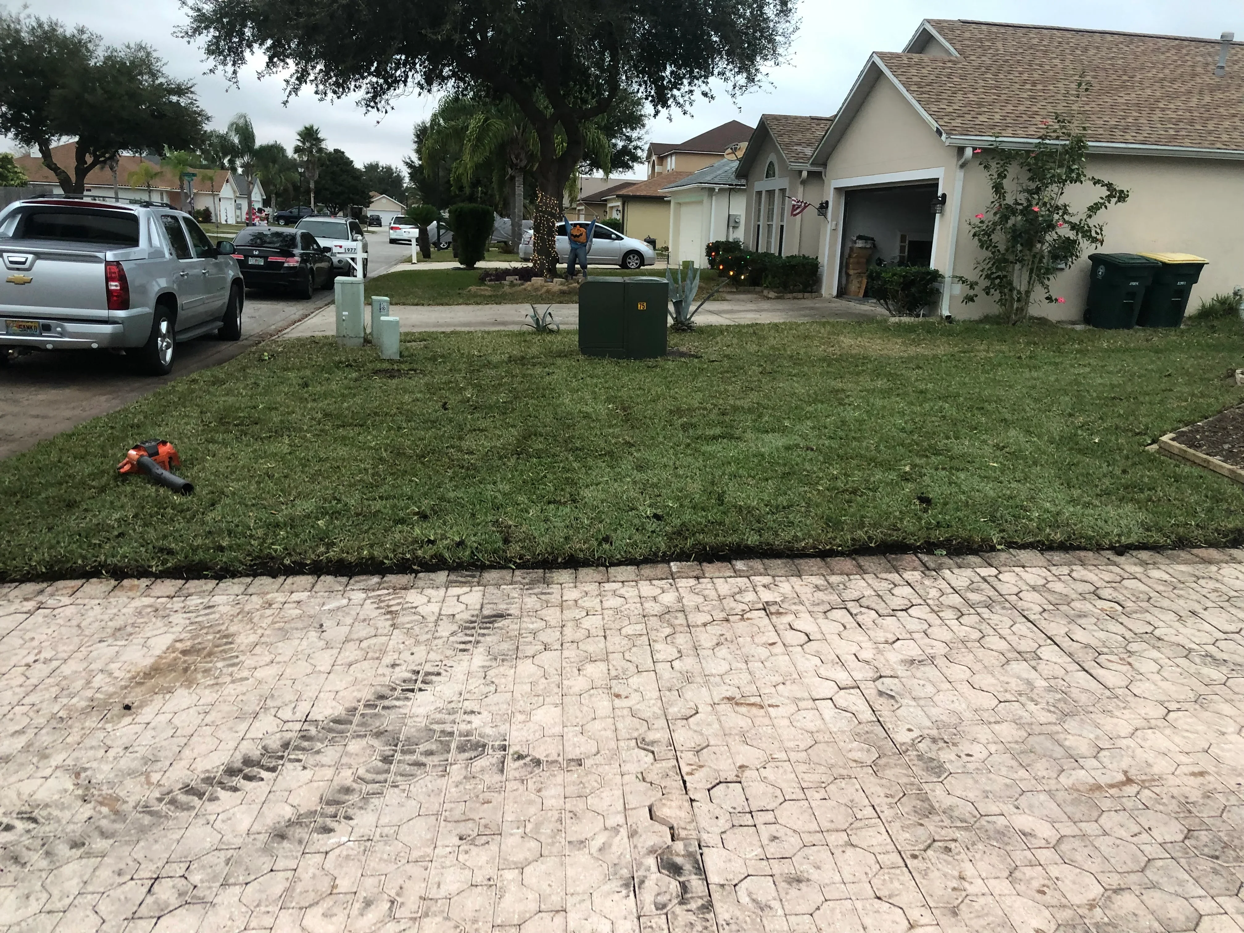 Permeable paver driveway with geometric pattern and newly installed sod lawn with edging
