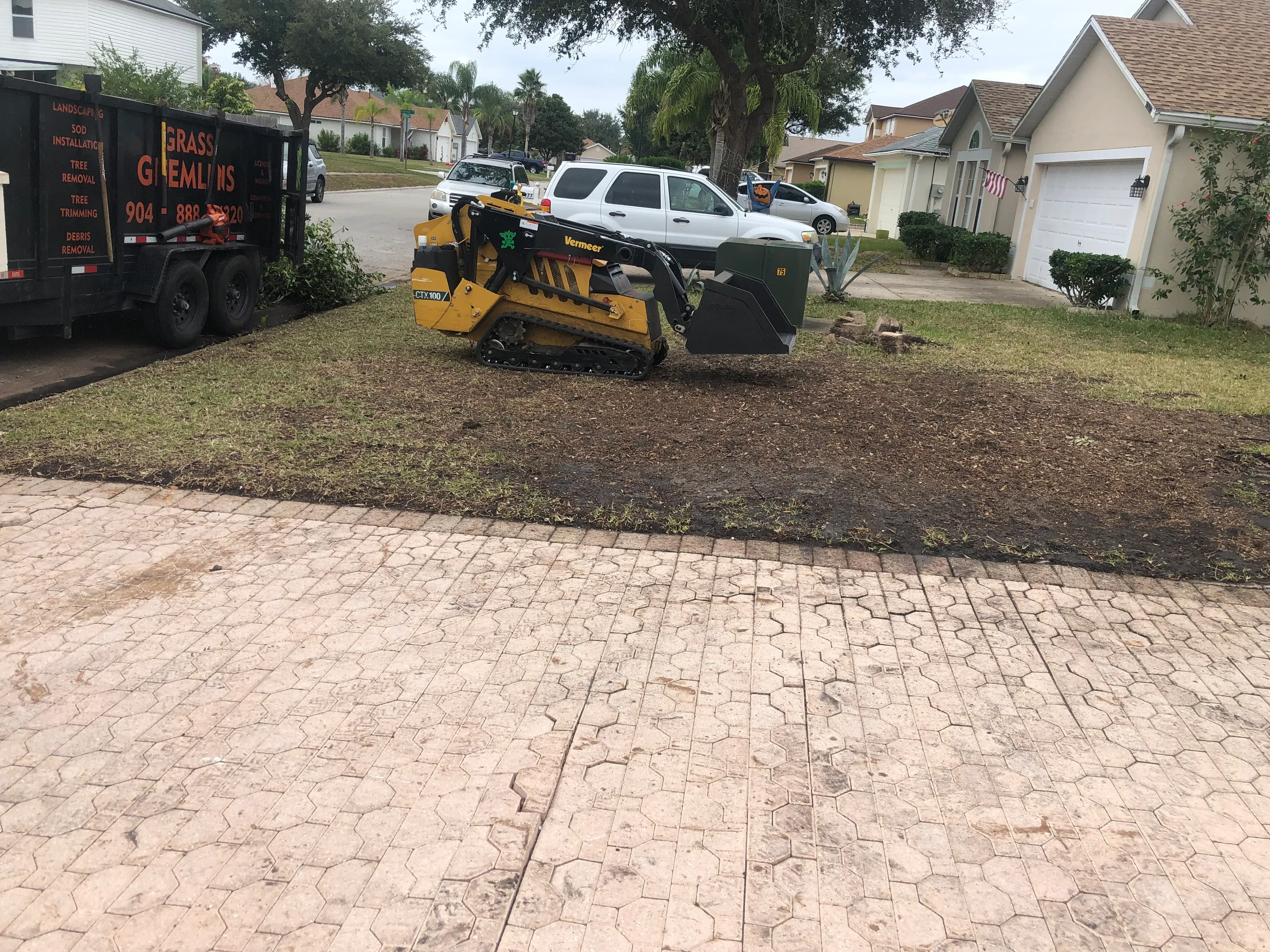 Vermeer track loader clearing overgrown lot with debris removal equipment on residential property