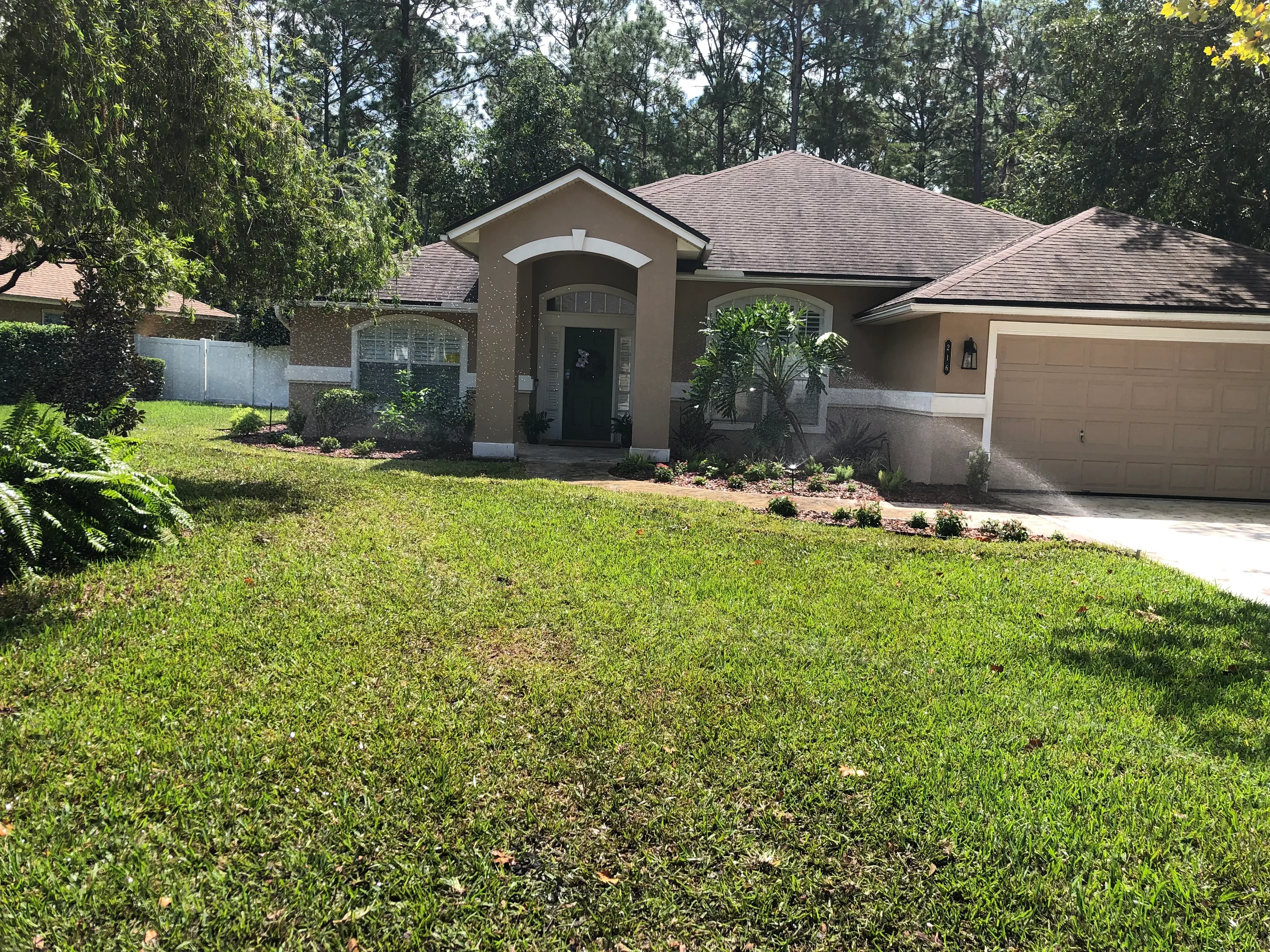 Newly installed sod lawn with mulched planting beds, ornamental shrubs, and landscape edging in front of residential home