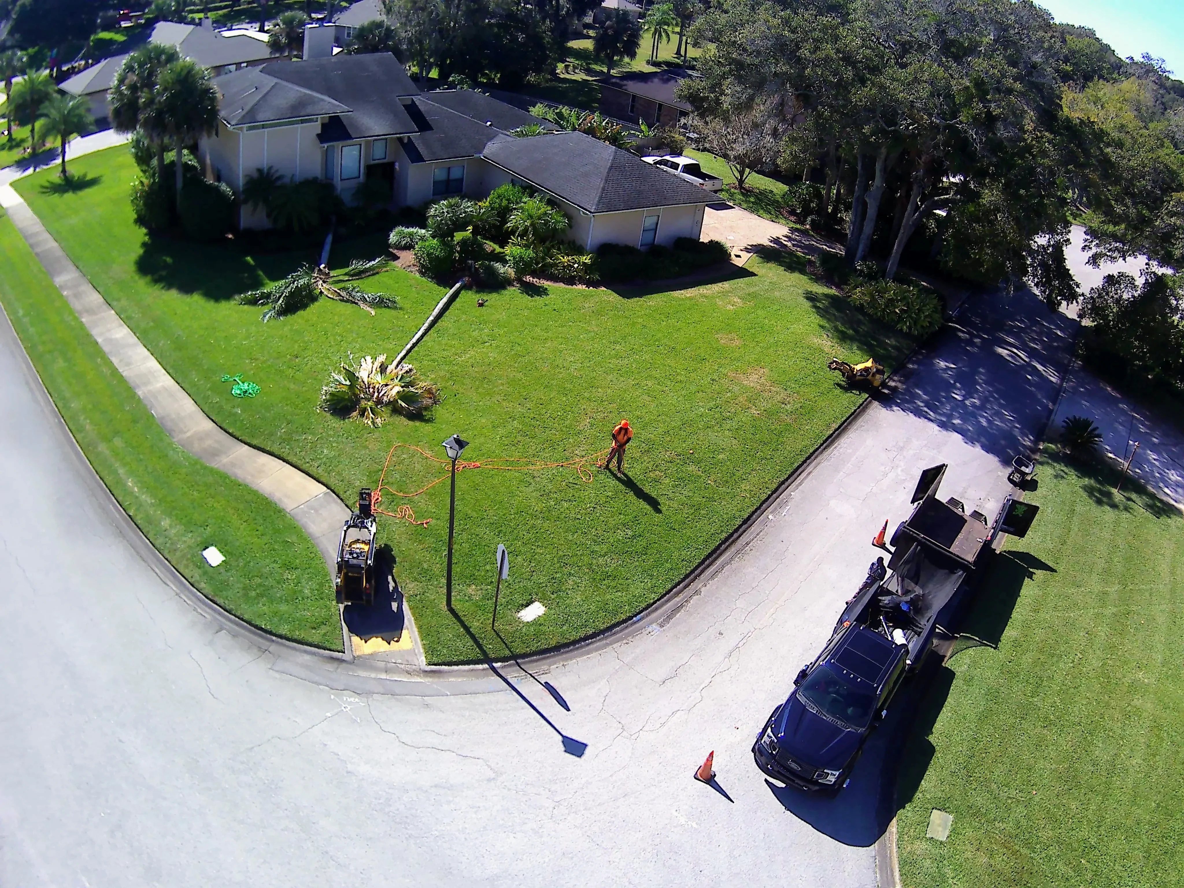 Aerial view of freshly mowed residential lawn with professional edging, equipment visible on driveway