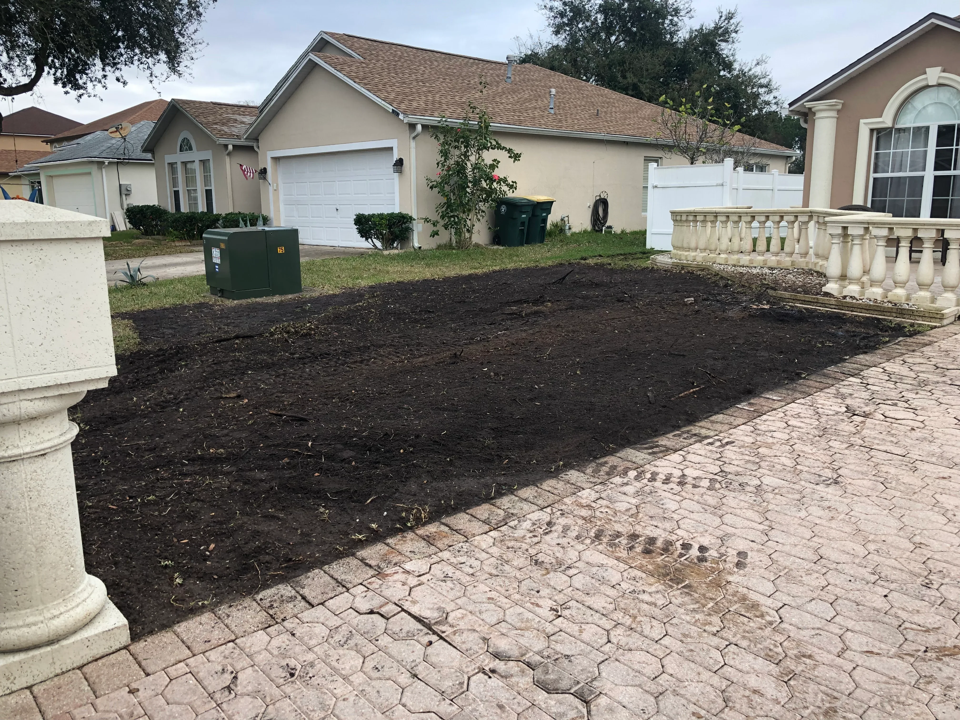 Dark mulch bed installation with brick paver edging along residential front yard