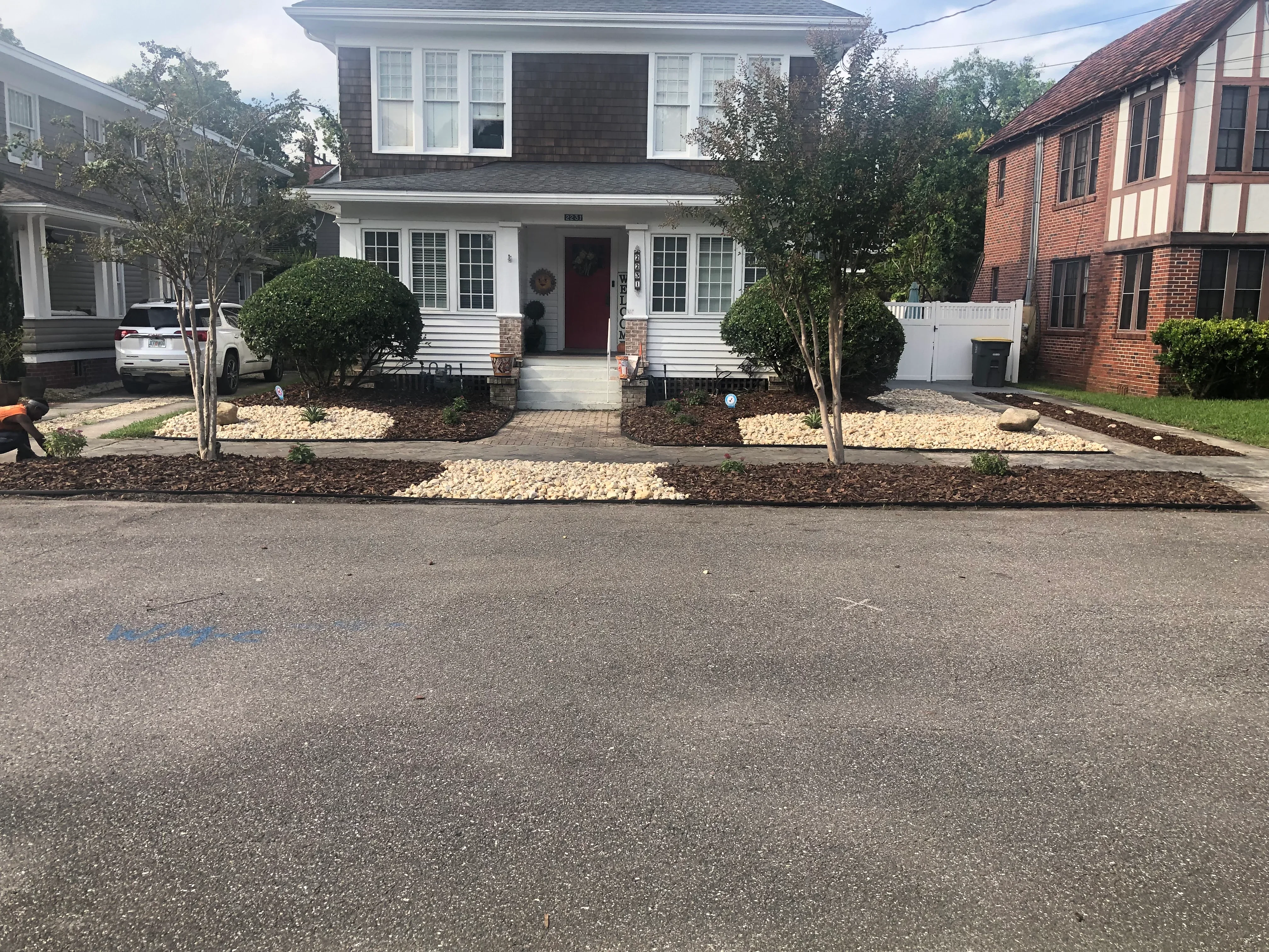 Front yard with mulch beds, light stone accents, young trees, and boxwood plantings